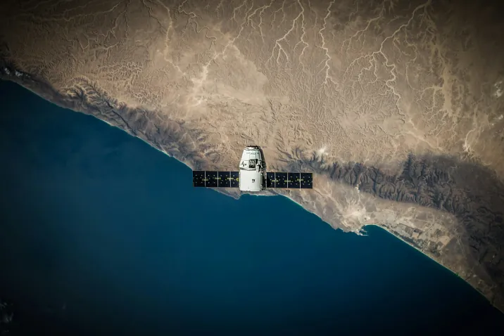 Satellite in orbit above a desert coastline
