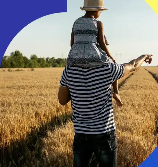 Parent and child walking through a sunlit wheat field