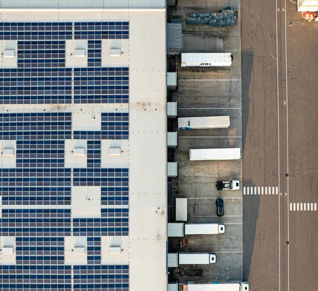 Aerial view of a solar-roofed warehouse with trucks at its loading docks