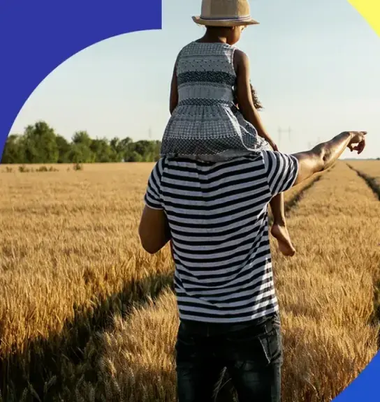 Parent and child walking through a sunlit wheat field